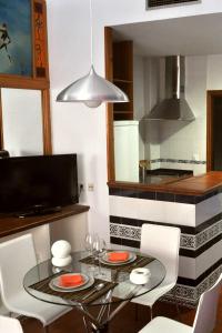 uma cozinha com uma mesa de vidro e cadeiras brancas em Sevillarent em Sevilha