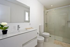 a white bathroom with a toilet and a glass shower at Marieta bajo in Colònia De Sant Jordi