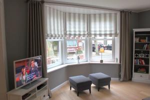 Una sala de estar con televisión y una ventana. en Dat Stadthus, en Wyk auf Föhr