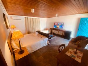 a bedroom with a bed and a table and a couch at POUSADA CHARLOTTE in Tiradentes