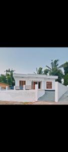 a large white house with trees in the background at HillNest Homes in Ambalavayal