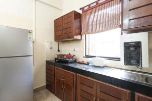 a kitchen with wooden cabinets and a white refrigerator at Vacation homestay Goa in Aguada