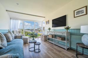 a living room with a blue couch and a flat screen tv at No 1 The Salcombe in Salcombe