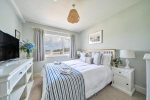 a white bedroom with a bed and a window at Flat 1 The Salcombe in Salcombe