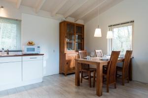 a kitchen and dining room with a wooden table and chairs at Valkenhoek (4p) in Ballum