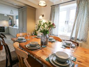 a dining room table with a vase of flowers on it at Dyffryn Cottage in Cardigan