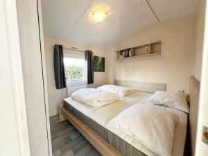 a bedroom with two beds and a window at Chalet 7a op Recreatiepark De Wielen in Sint Maarten +17 photos
