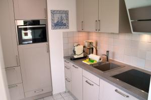 a kitchen with white cabinets and a sink at Linn in Oldsum