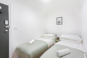 two beds in a room with white walls at London Central Suits - Comfortable Rooms in London