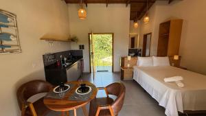 a bedroom with a bed and a table and a kitchen at Estúdio Ilhote da Prainha in Ilhabela