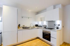 een witte keuken met witte kasten en apparaten bij Tooley Street Apartments by Viridian Apartments in Londen