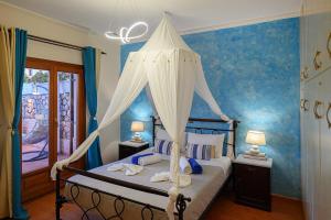 a bedroom with a canopy bed with blue walls at Villa Helena Santorini- Private Plunge Pool & BBQ in Mesaria +27 photos