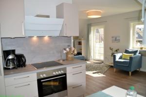a kitchen with a stove top oven next to a living room at Maisfeld Wohnung in Wyk auf Föhr