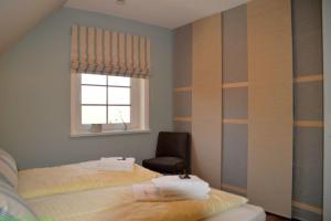 a bedroom with two beds and a chair and a window at Maisfeld Wohnung in Wyk auf Föhr