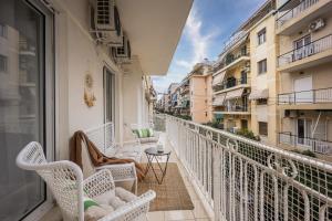 a balcony with white chairs and a table and buildings at Elegant Aphrodite, 2 Bedroom Apartment, by Acropolin in Athens