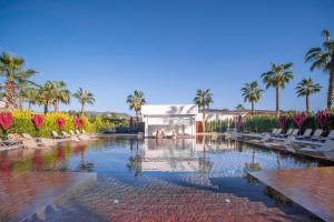 ein Pool mit Liegestühlen und Palmen und ein Gebäude in der Unterkunft Serenity Queen Hotel in Alanya