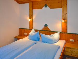 um quarto com uma cama com almofadas azuis e brancas em Apartment Kassler-1 by Interhome em Kappl