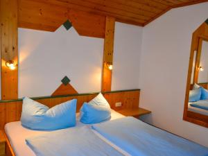 a bedroom with a bed with blue pillows and a mirror at Apartment Kassler-1 by Interhome in Kappl +17 photos