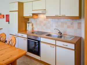 uma cozinha com armários brancos, um lavatório e uma mesa em Apartment Kassler-1 by Interhome em Kappl