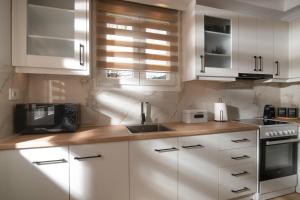 une cuisine avec des armoires blanches, un évier et un micro-ondes dans l'établissement Villa Destiny, à Lagópodhon