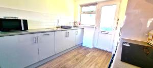 eine Küche mit weißen Schränken und einer Spüle und einem Fenster in der Unterkunft 8 Penhale in Perranporth + 4 Fotos