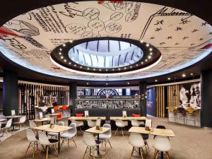 a restaurant with tables and chairs and a large ceiling at ibis Birmingham Centre New Street Station Hotel in Birmingham