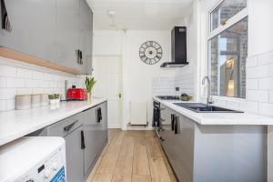 a white kitchen with a sink and a counter at 3 Bedrooms & 2 Showers - Home From Home in Newcastle under Lyme