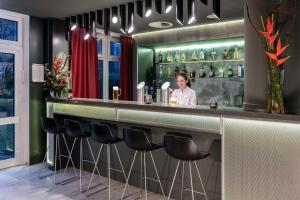 a woman standing behind a bar in a restaurant at NH Collection Hamburg City in Hamburg +31 photos