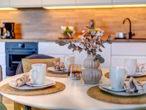 a table with plates and cups and a vase with flowers at Bernsteinquartier BQ 0108 in Kolpinsee