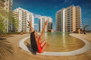 a woman in a red dress sitting in the water at Ground Garden View Apartments in Caesar Resort & SPA, Long Beach in Perivolia tou Trikomou