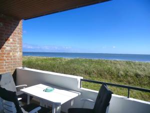 a table and chairs on a balcony with a view of the ocean at Dünennest in Südstrand