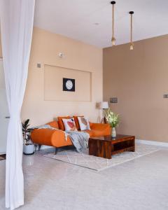 Moonlight Manor- Luxury Escape في بانغالور: غرفة معيشة مع أريكة برتقالية وطاولة قهوة +27 صورة