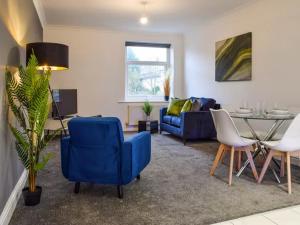 a living room with a blue chair and a table at St John's Newsome Serviced Apartments in Huddersfield
