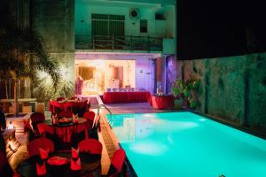 a large swimming pool with red tables and chairs at Ismattha Hotel in Anuradhapura