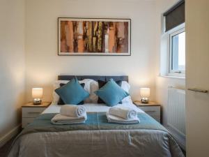 a bedroom with a bed with blue and white pillows at St John's Newsome Serviced Apartments in Huddersfield