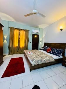 une chambre avec un lit et un ventilateur de plafond dans l'établissement Rosewood Cottage, à Karachi