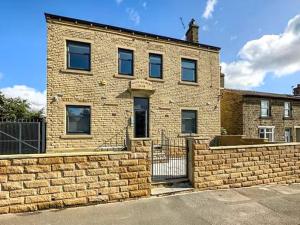 a brick building with a fence in front of it at St John's Newsome Serviced Apartments in Huddersfield