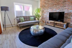 a living room with a couch and a tv at SHINYHOMEZ - Familienfreundliche Ferienwohnung in Geestland am Wattenmeer mit Terrasse, Küche und WLAN in Neuenwalde