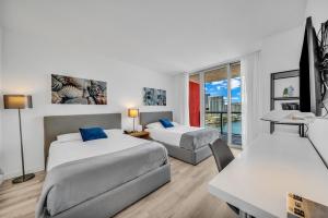 a hotel room with two beds and a table and a desk at BeachWalk Studio Apmt 2 Beds with Beach Service 2103 in Hallandale Beach