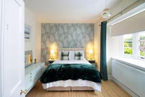 a bedroom with a large bed and two windows at Whatton Cottage in Gullane