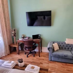 a living room with a couch and a desk with a computer at Victoria Apartment 1901-Apartament ultracentral Oradea ,lângă Piața Unirii in Oradea