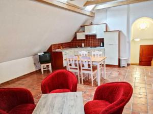 een keuken en eetkamer met rode stoelen en een tafel bij Statek u Badyho in Dolní Třebonín