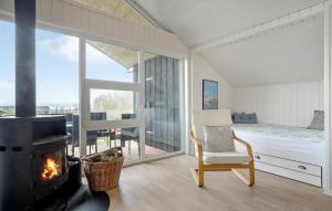 a room with a fireplace and a bed and a chair at 3 Bedroom Amazing Home In Spøttrup in Lihme