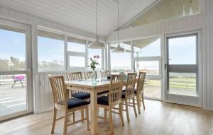 a dining room with a table and chairs and windows at 3 Bedroom Amazing Home In Spøttrup in Lihme