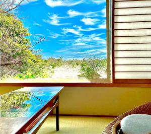 a window with a view of a beach at Cozy Villa with Hot springs and Nature in Ito