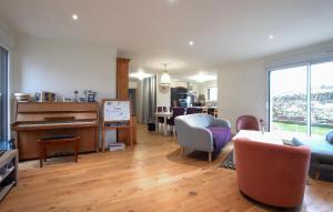 a living room with a piano and a table and chairs at 3 Bedroom Nice Home In Amfreville in Amfréville