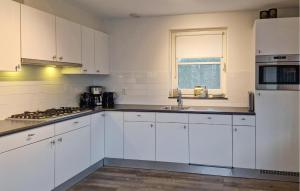 a white kitchen with white cabinets and a window at Bodelaeke-Schiphuis Wellness 8 in Giethoorn +11 photos