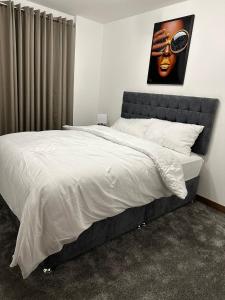 a bedroom with a large bed with a painting on the wall at Charming Dartford Apartment Retreat in Dartford