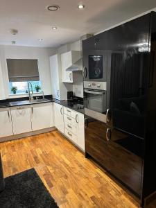 a kitchen with black and white appliances and wooden floors at Charming Dartford Apartment Retreat in Dartford