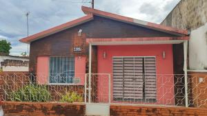 a red and black house with a fence at Casa de 90m2 toda sua aconchegante e central in Corumbá